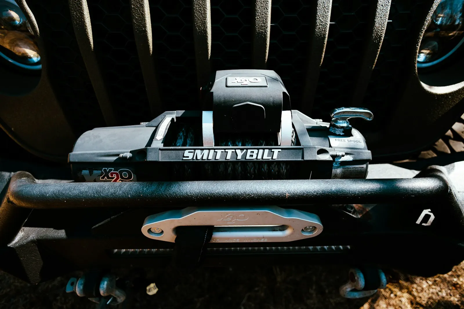 Winch with synthetic rope and a fairlead on a steel front bumper, with shackles below
