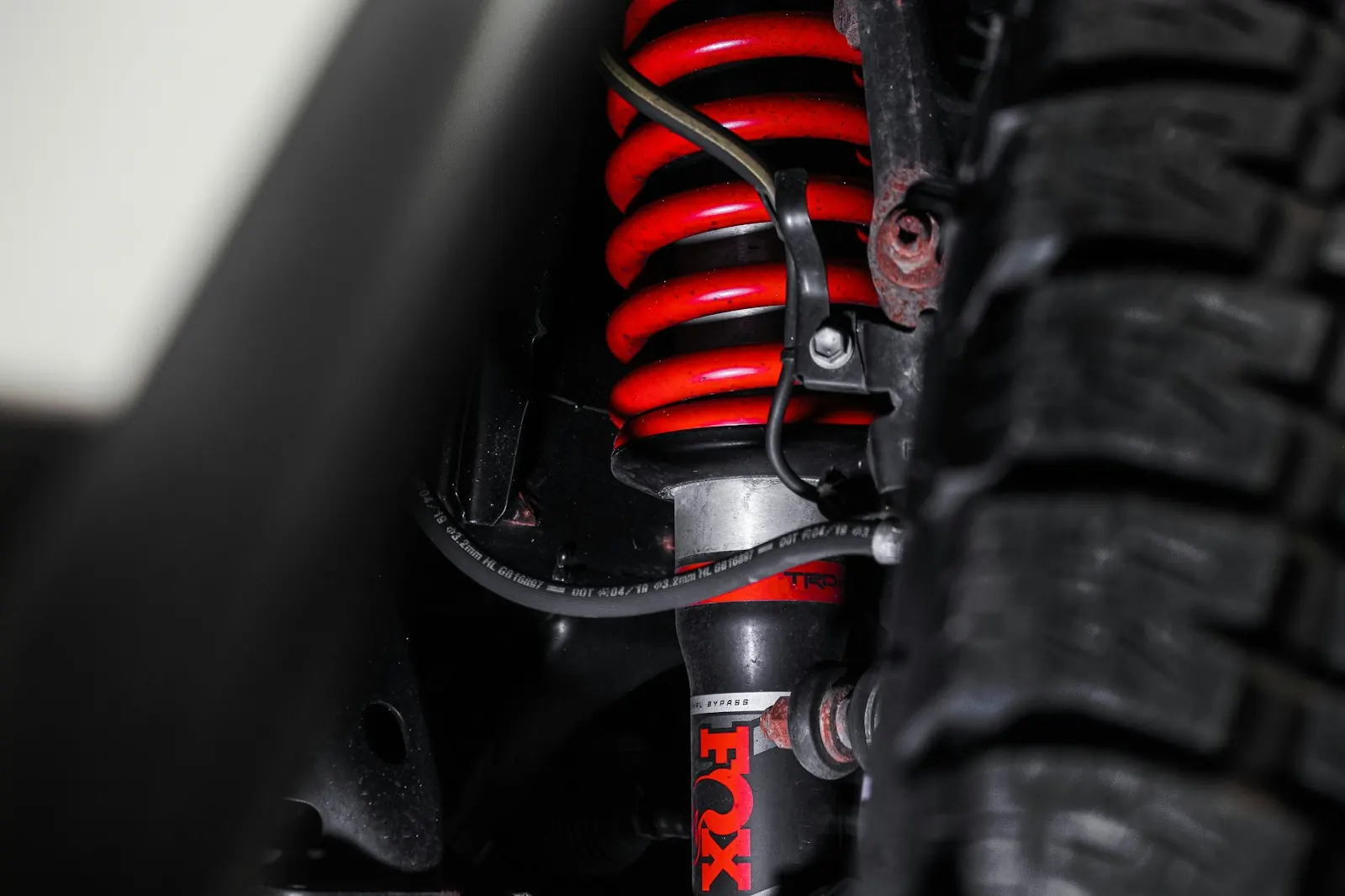 Red coil spring over an aftermarket shock behind a mud-terrain tire