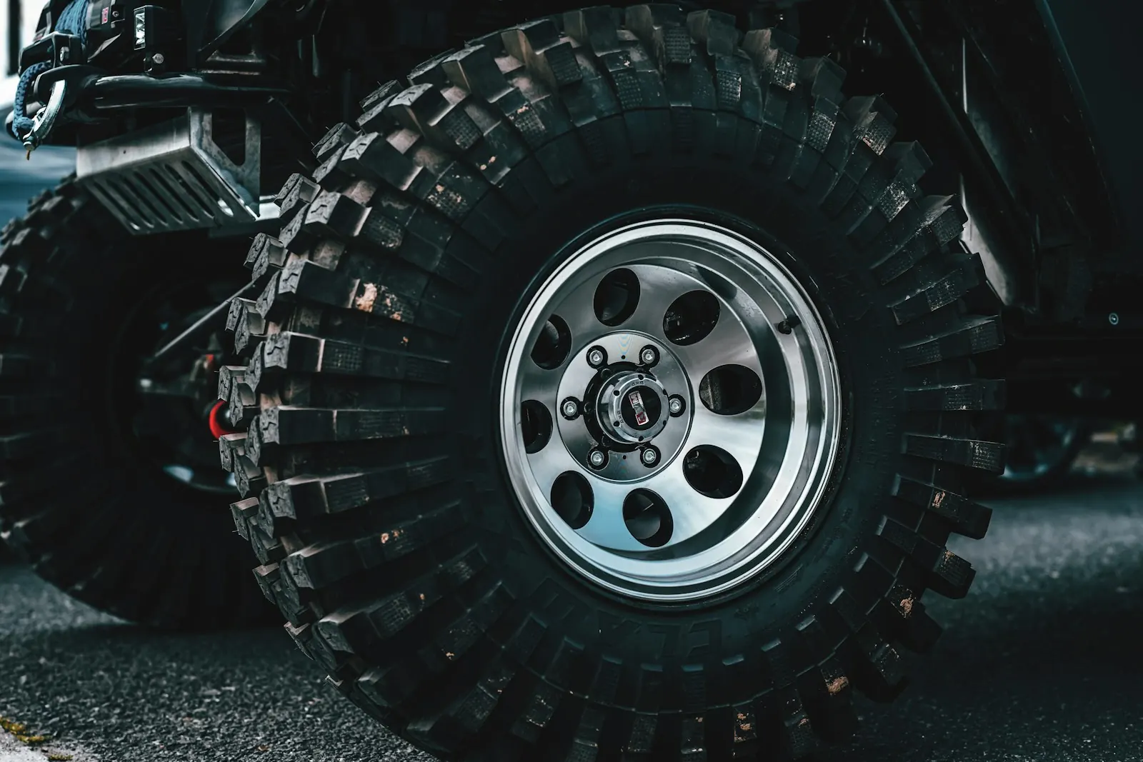 Large knobby off-road tires on polished eight-hole wheels on a parked 4x4