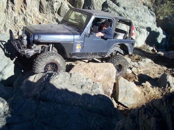 Jeep on rock ledge — suspension in play
